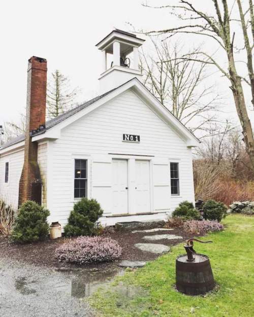 A small white building with a bell tower, labeled "No. 1," surrounded by greenery and a gravel path.