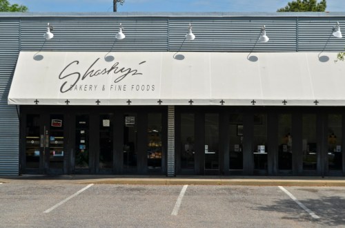 Exterior of Shashy's Bakery & Fine Foods, featuring a large awning and glass doors, with parking spaces in front.