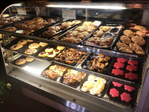A display case filled with various baked goods, including pastries, cookies, and colorful desserts.