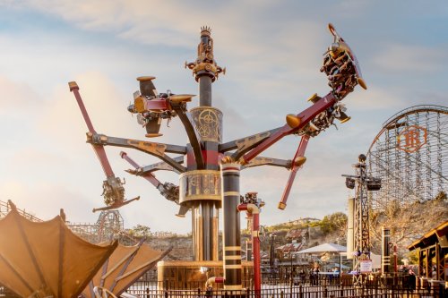 A thrilling amusement park ride with spinning seats and a towering structure, set against a scenic backdrop.