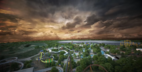 Aerial view of an amusement park with rides, water attractions, and lush greenery under a dramatic sky.