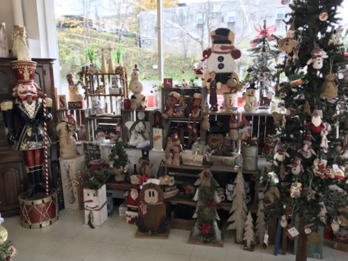 A festive display of holiday decorations, including snowmen, nutcrackers, and Christmas trees, in a cozy shop setting.