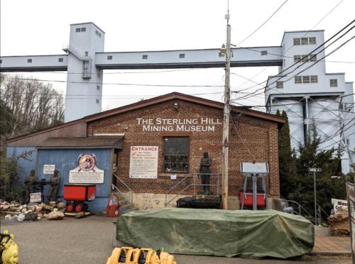 Exterior of the Sterling Hill Mining Museum, featuring a brick building and mining equipment in front.