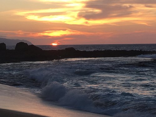 A serene beach scene at sunset, with waves gently lapping at the shore and a colorful sky.