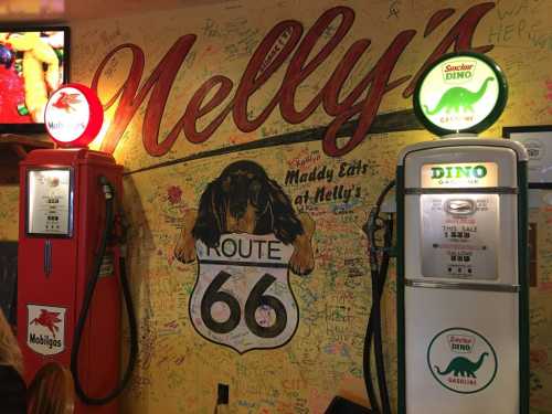 Vintage gas pumps beside a colorful mural featuring a dog and "Route 66" at Nelly's diner.