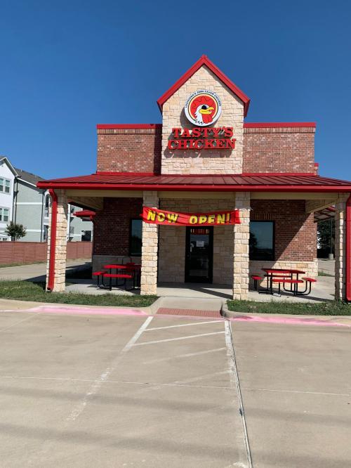 A fast-food restaurant named "Hasty's Chicken" with a red roof and a "Now Open!" banner. Clear blue sky in the background.