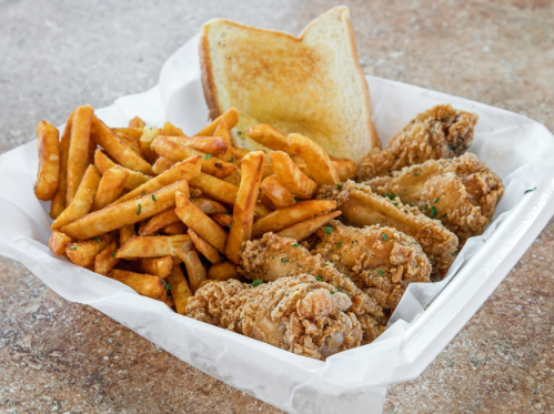 A tray of crispy fried chicken, golden fries, and a slice of toasted bread.