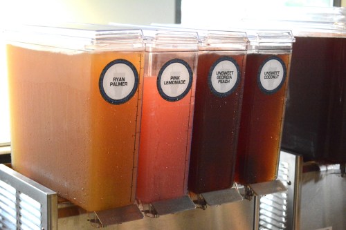 Four beverage dispensers labeled Ryan Palmer, Pink Lemonade, Unsweet Georgia Peach, and Unsweet Coconut.