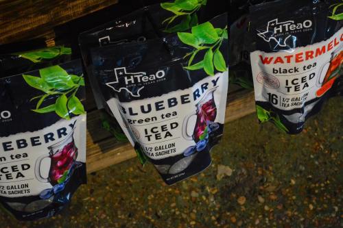 Pouches of H-Tea iced tea in blueberry and watermelon flavors hanging on a display.