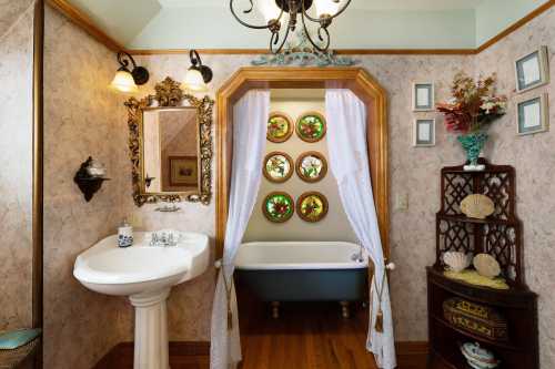 A vintage bathroom featuring a pedestal sink, a clawfoot tub, and decorative stained glass windows.