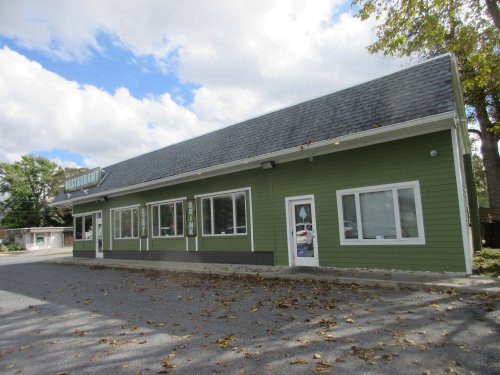 A green restaurant building with large windows, set against a partly cloudy sky.