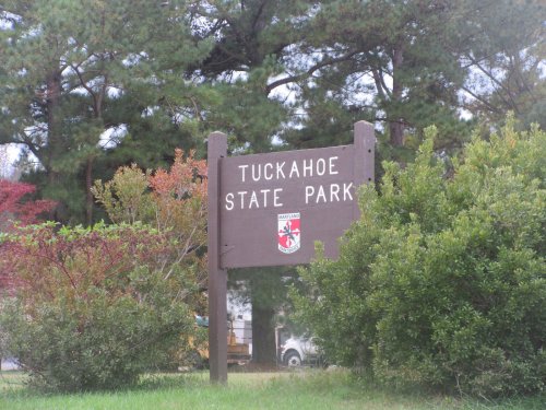 Sign for Tuckahoe State Park surrounded by greenery and trees.