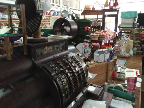 A vintage cash register in a quaint store filled with various goods and colorful displays.