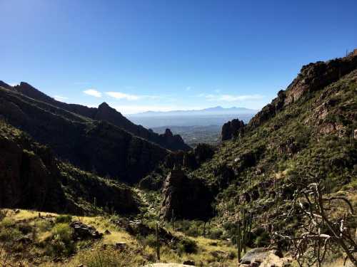 A scenic view of rugged mountains and valleys under a clear blue sky, with distant peaks visible on the horizon.