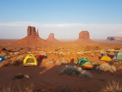 Tents set up in a desert landscape with iconic rock formations under a clear blue sky.