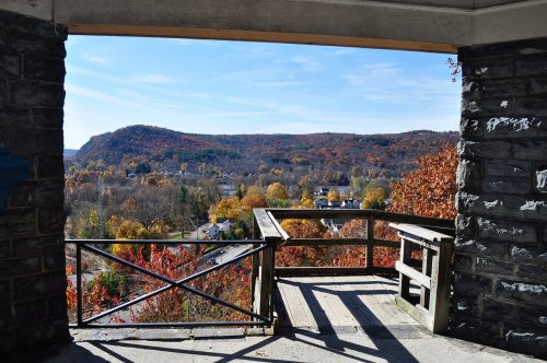 View from a stone overlook showcasing vibrant autumn foliage and rolling hills under a clear blue sky.