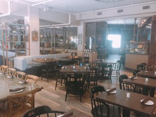 A spacious restaurant interior with wooden tables, chairs, and a cozy atmosphere, featuring a bar area in the background.