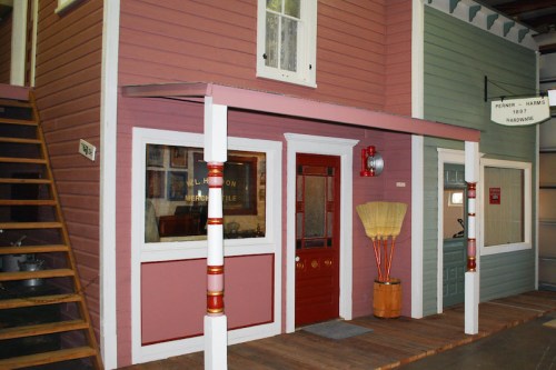 A colorful building facade with a porch, stairs, and large windows, resembling a small town storefront.