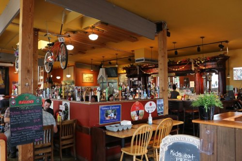 Cozy restaurant interior with wooden furniture, a bar, and a bicycle hanging from the ceiling.