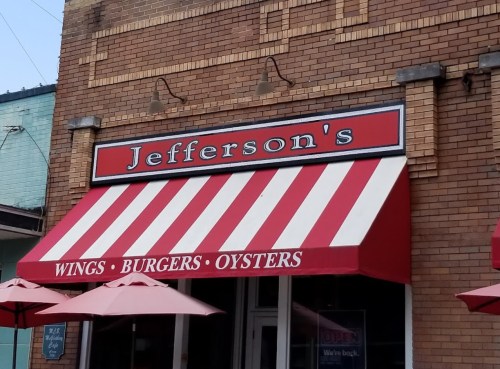 Red and white striped awning of Jefferson's restaurant, featuring "WINGS • BURGERS • OYSTERS" on the sign.