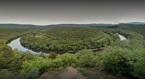 A panoramic view of a lush green landscape with winding rivers and rolling hills under a clear sky.