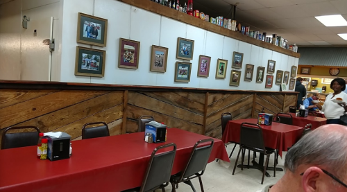 Interior of a diner with red tablecloths, wooden walls, and framed photos on display.