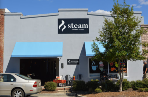 Exterior of a coffee shop named "steam coffee & cream," featuring blue awnings and a welcoming entrance.