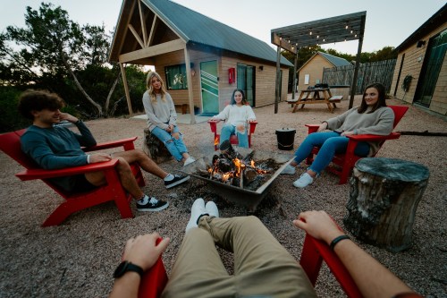 A group of four friends sitting around a fire pit in a cozy outdoor setting, enjoying a relaxed evening together.