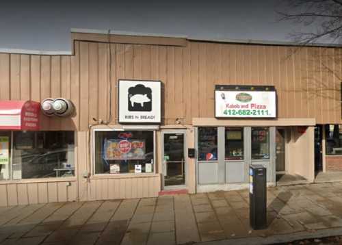 Exterior of a restaurant with signs for "Ribs N Bread" and "Kabob and Pizza," featuring a simple storefront design.