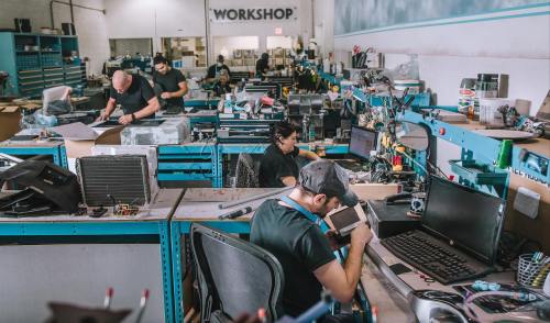 A busy workshop with several people working at desks, surrounded by tools and equipment.