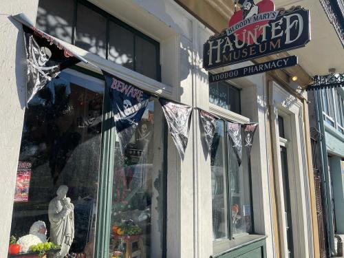 Exterior of Bloody Mary's Haunted Museum, featuring a sign, pirate-themed decorations, and a statue in the window.