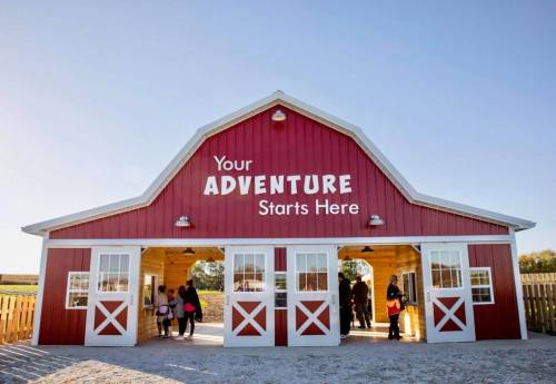 A red barn with the text "Your ADVENTURE Starts Here" above the entrance, welcoming visitors.