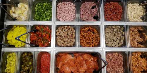 A variety of toppings in containers, including meats, vegetables, and seasonings, arranged in a grid layout.