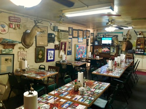 A rustic dining room with wooden tables, chairs, and walls adorned with taxidermy, vintage decor, and memorabilia.