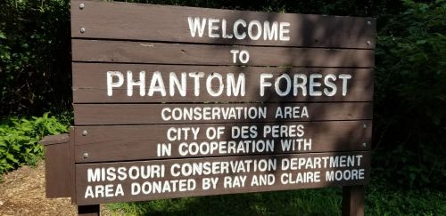 Sign welcoming visitors to Phantom Forest Conservation Area, listing cooperation with local and state conservation departments.