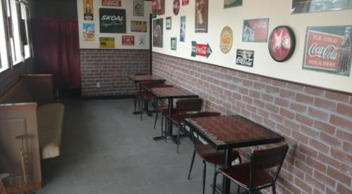 A cozy cafe interior with brick walls, small tables, and vintage signs, creating a warm, inviting atmosphere.