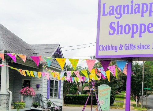 A colorful storefront with a sign reading "Lagniappe Shoppe" and festive banners strung across the front.