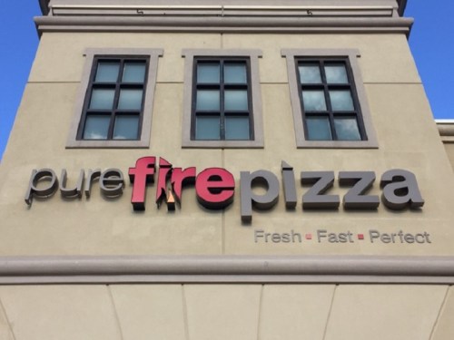 Sign for "pure fire pizza" with the tagline "Fresh - Fast - Perfect" on a building exterior.