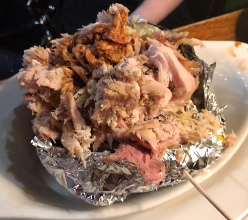 A plate of shredded chicken piled on a bed of lettuce, served in a foil wrap.