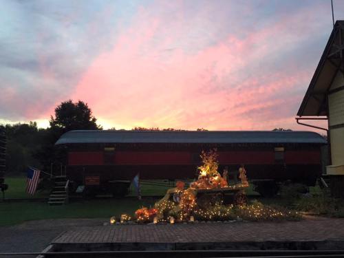 A vintage train car against a colorful sunset, with festive decorations and lights in the foreground.