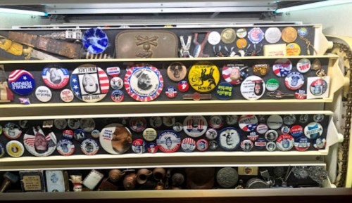 A display case filled with various political buttons and pins, showcasing a range of designs and colors.