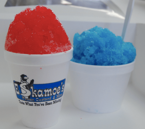 Two cups of shaved ice, one red and one blue, with a logo for E Shakamoes Frozen Custard & More.