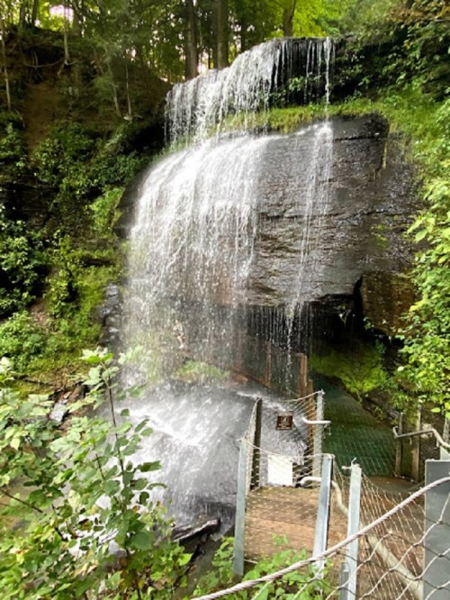 A serene waterfall cascading over rocky cliffs, surrounded by lush greenery and trees.