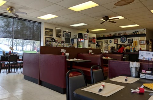 Interior of a casual diner with red booths, tables set for dining, and various photos on the walls.