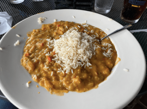 A plate of curry with rice on top, served in a casual dining setting.