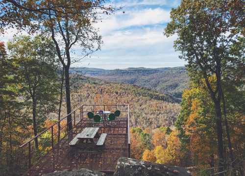 A scenic overlook with a picnic table and chairs, surrounded by colorful autumn trees and rolling hills in the distance.