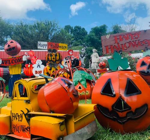 Colorful Halloween decorations featuring pumpkins, ghosts, and festive signs in a vibrant outdoor setting.