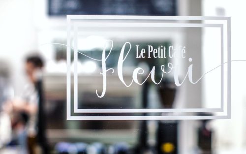 A window decal reading "Le Petit Café Fleuri" with a blurred figure in the background.