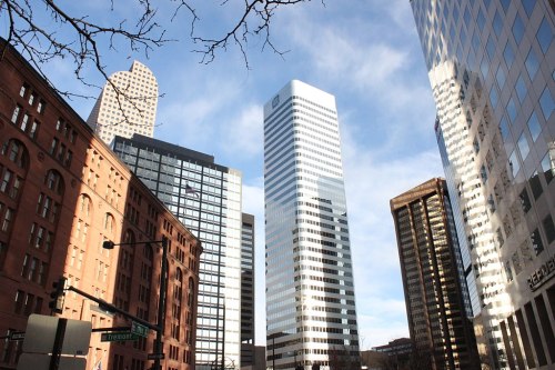 Cityscape featuring a mix of modern skyscrapers and historic buildings under a blue sky with scattered clouds.