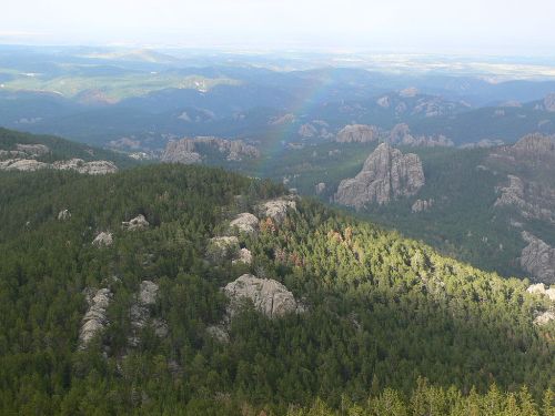 A panoramic view of lush green mountains and rocky formations under a cloudy sky.